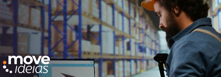 Profissional de logística com capacete monitora o ciclo de pedidos em um laptop dentro de um armazém, garantindo o cumprimento do SLA de transporte e a visibilidade completa da operação
